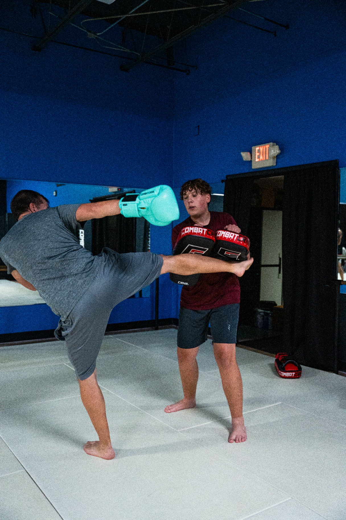 High kick to partner-held pads during adult kickboxing class at FIT Beyond Plus in Tullahoma