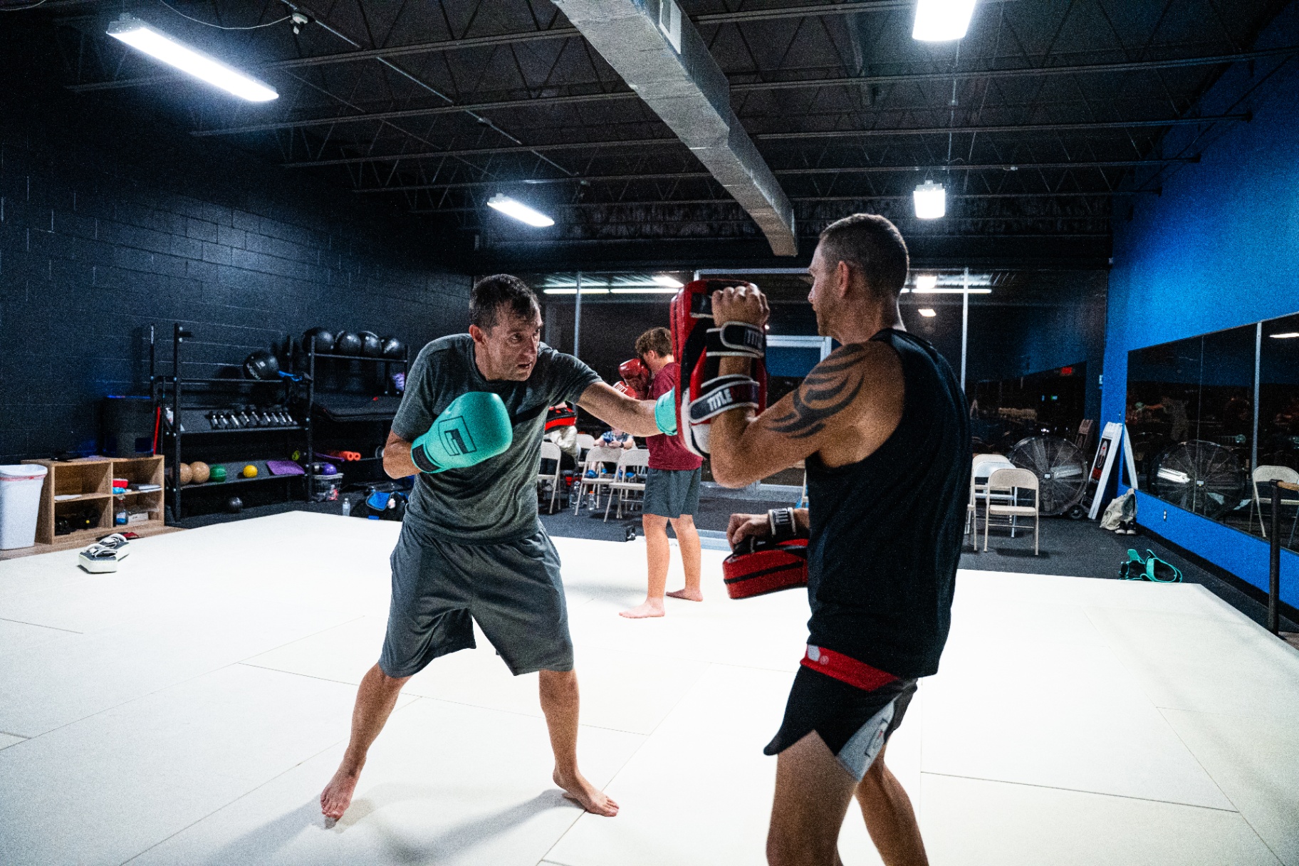 Adult kickboxing partner pad work with teal gloves at FIT Beyond Plus in Tullahoma